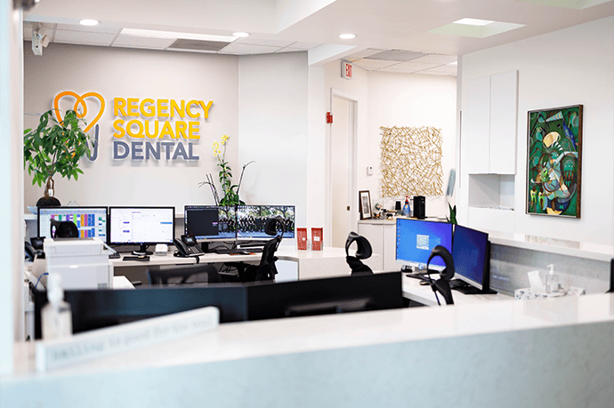 The big, clean reception area at Regency Square Dental, with the logo wall behind the front desk.